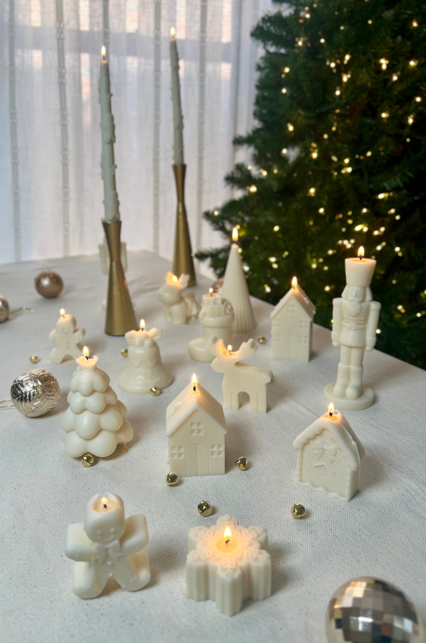 Decorative Christmas scene with white candles and ornaments on a table.