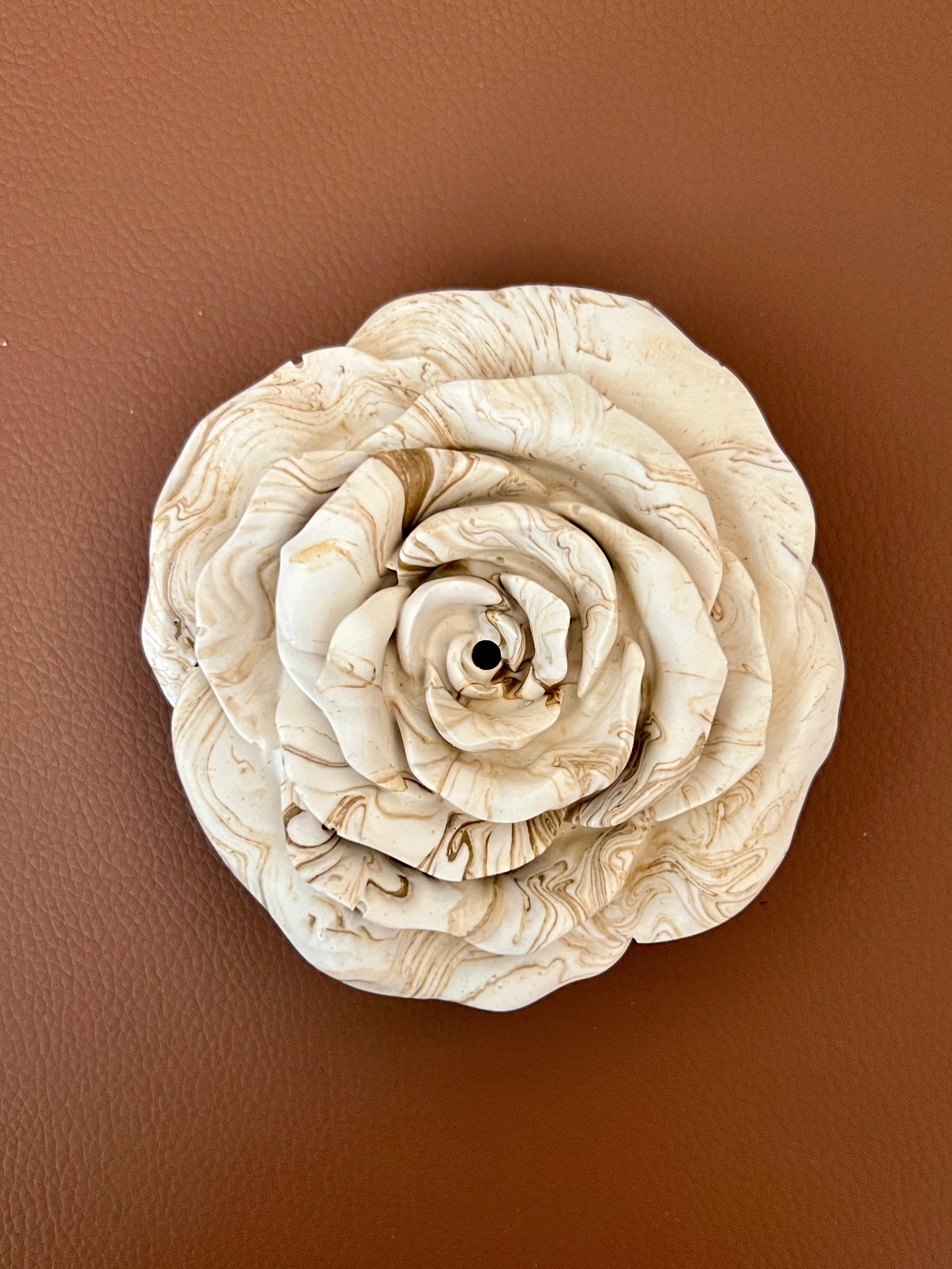 White rose-shaped incense holder on a brown leather surface