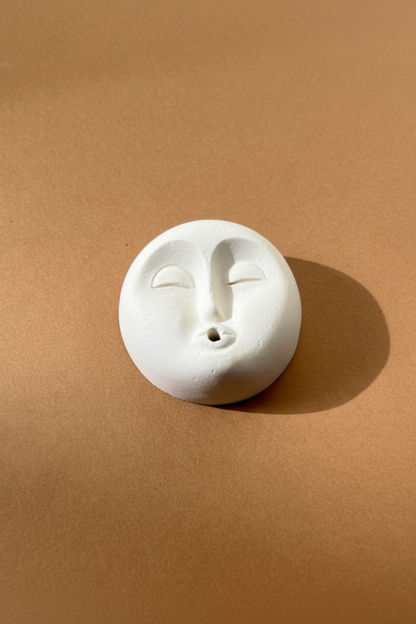 white moon shaped incense holder on a brown background

