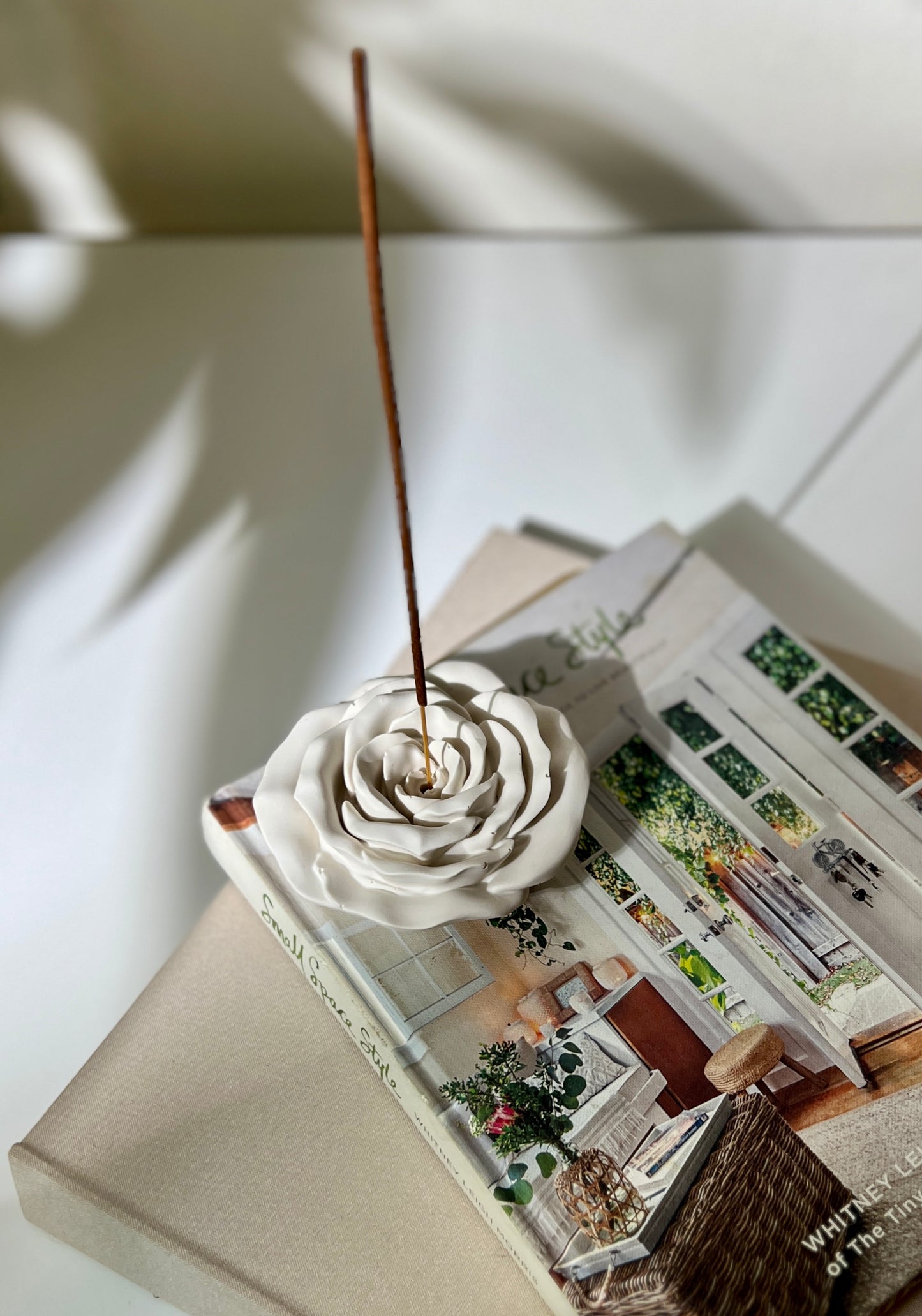 rose shaped incense holder with Incense stick in a decorative holder on top of a magazine