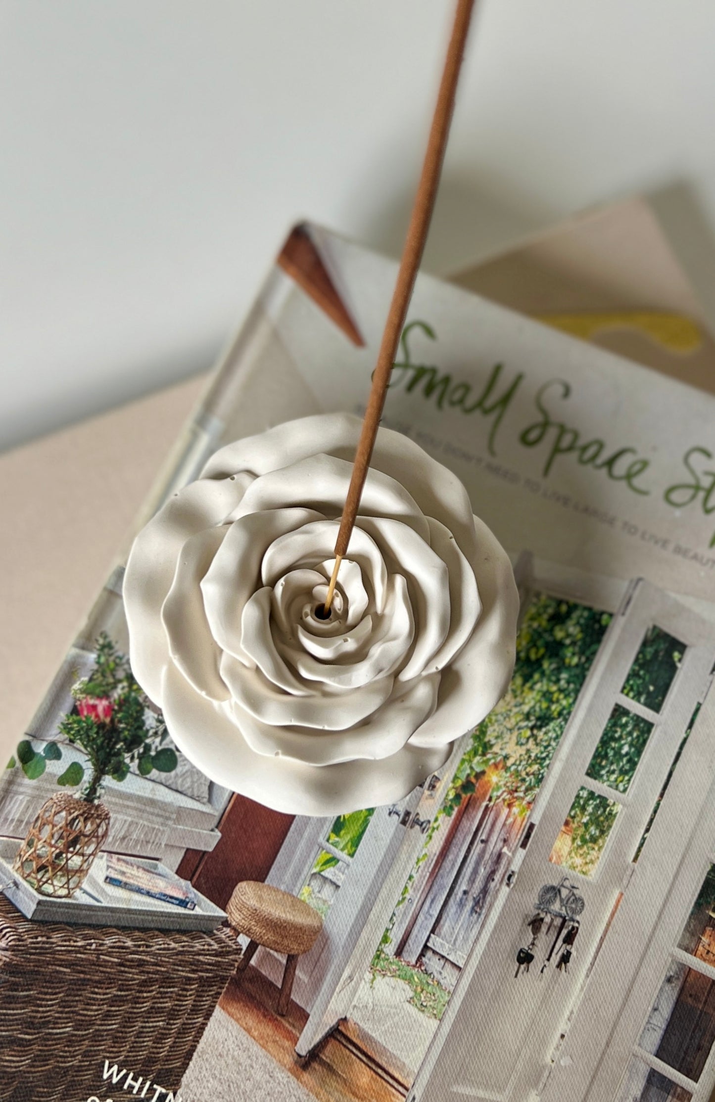 White ceramic incense holder shaped like a flower on top of a magazine